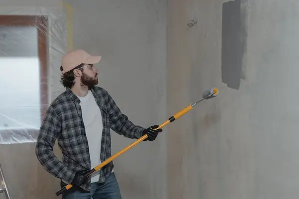 Painter rolling grey paint onto an interior wall in Chicago